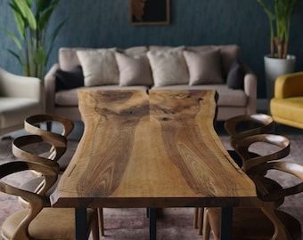 May include: A long, wooden dining table with a live edge design. The table is made of light brown wood with a natural grain pattern. It is surrounded by six chairs with curved backs and seats.