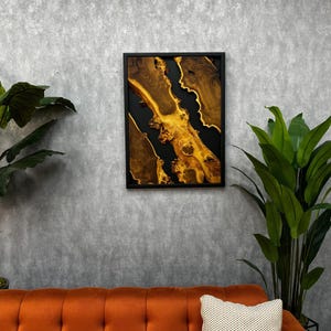 May include: A framed abstract art piece featuring a black and gold resin design. The resin is poured into a wooden frame, creating a unique and modern look.