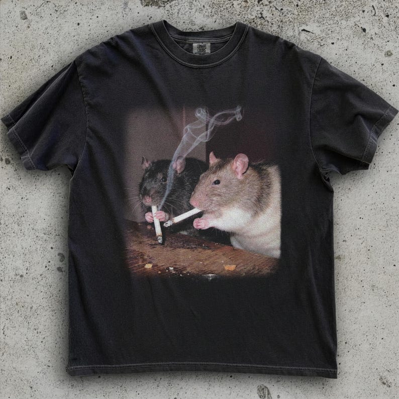 Puede incluir: Camiseta gris oscuro con un gr&aacute;fico de dos ratas fumando cigarrillos. Una rata es negra, la otra es marr&oacute;n y blanca. El humo se eleva de los cigarrillos. La camiseta tiene cuello redondo y mangas cortas.