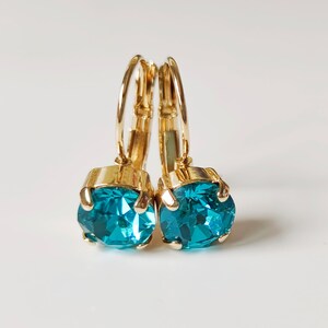 May include: A pair of gold hoop earrings with turquoise blue gemstone accents.