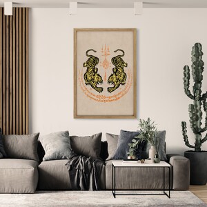 Pode incluir: Uma impress&atilde;o emoldurada de uma obra de arte tradicional tailandesa com dois tigres pretos e amarelos frente a frente em um c&iacute;rculo de escrita laranja e vermelha. Os tigres est&atilde;o em uma postura protetora com as patas levantadas. A escrita est&aacute; em tailand&ecirc;s.