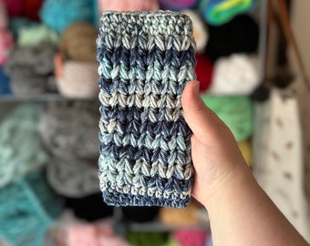 May include: A crocheted phone case in shades of blue and white. The case has a textured, striped pattern.
