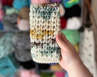 May include: A crocheted headband with a white base and stripes of brown, green, and yellow yarn.