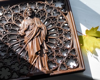 May include: A detailed wooden carving of a religious figure, standing in front of an ornate, openwork background. The figure is depicted with a beard and flowing robes. The carving is set within a rectangular frame, and the overall color is a warm brown.