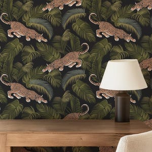 May include: A room featuring a wooden desk, chair, and a lamp. The wall is covered in wallpaper with a repeating pattern of leopards and tropical leaves in shades of green, black, and tan. The overall theme is a jungle or safari.
