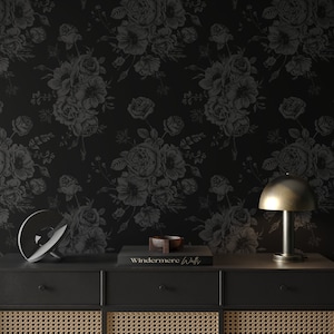 This image showcases the wallpaper pattern in an accent wall mockup. The wallpaper pattern has a solid black background with subtle dark grey floral illustrations.