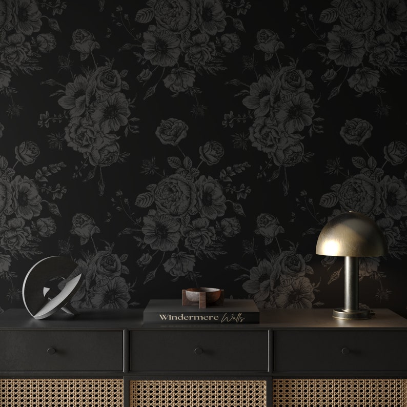 This image showcases the wallpaper pattern in an accent wall mockup. The wallpaper pattern has a solid black background with subtle dark grey floral illustrations.