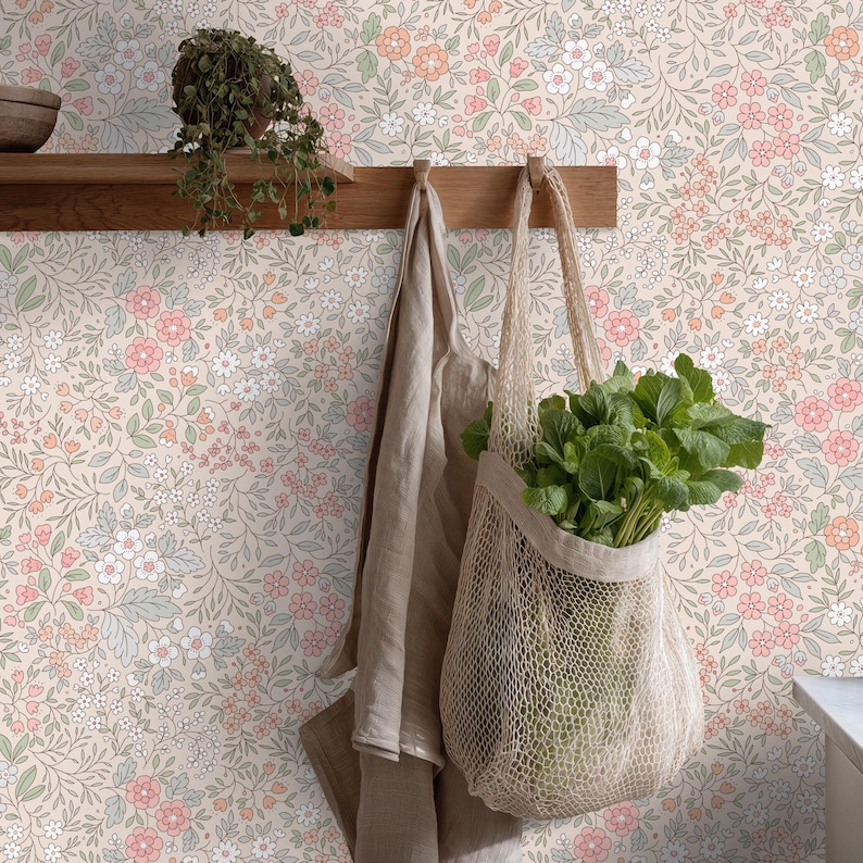 This image showcases the wallpaper pattern in a kitchen pantry setting. The pattern features a ditsy floral blossom design. The flowers are illustrated in shades of peach, coral, pink, and white against a beige background.