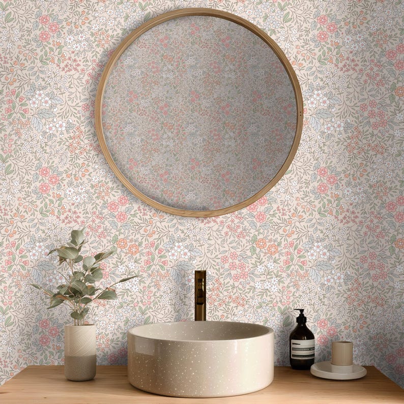 This image showcases the wallpaper pattern in a bathroom setting. The pattern features a ditsy floral blossom design. The flowers are illustrated in shades of peach, coral, pink, and white against a beige background.