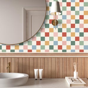 May include: A bathroom with a round mirror, a wooden vanity, and a checkered wallpaper with red, green, blue, yellow, and pink squares. There are two white tubes of hand cream on the counter.
