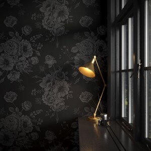 This image showcases the wallpaper pattern in an accent wall mockup. The wallpaper pattern has a solid black background with subtle dark grey floral illustrations.