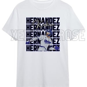 Puede incluir: Camiseta blanca con un gráfico de un jugador de béisbol con uniforme de los Dodgers. El diseño incluye el nombre "Hernandez" apilado en fuente púrpura, con "Kike" en cursiva sobre la imagen del jugador.