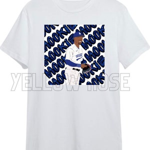 May include: White t-shirt with a blue and white illustration of a baseball player with the word "Mookie" repeated in a blue glittery pattern.