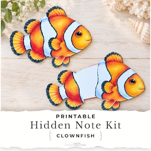 May include: Two clownfish-shaped paper cutouts with orange, white, and black markings. One fish is closed, and the other is partially open to reveal a white interior. The text below reads: PRINTABLE Hidden Note Kit { CLOWNFISH } Journal Works Studio.