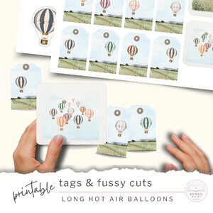 May include: A collection of printable tags and fussy cuts featuring watercolor illustrations of hot air balloons over a green landscape. The set includes individual balloon cutouts and rectangular tags with eyelets, labeled printable tags & fussy cuts long hot air balloons.