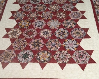 May include: A red, white, and blue quilt with a geometric pattern of stars and circles. The quilt is made of fabric with a teddy bear print.