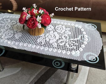 Puede incluir: Un camino de mesa de crochet blanco con un delicado patrón floral. El camino de mesa está sobre una mesa de vidrio negro con un jarrón de flores rojas y blancas en el centro. El texto "Crochet Pattern" es visible en la esquina superior derecha de la imagen.