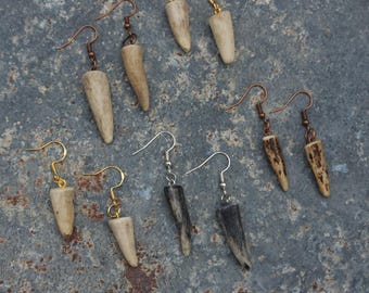 Peut inclure: Une collection de boucles d'oreilles en corne faites à la main, avec des crochets de différentes couleurs, or, argent et cuivre. Les boucles d'oreilles présentent des morceaux de bois de cerf naturels et clairs, certains avec des motifs texturés plus foncés.