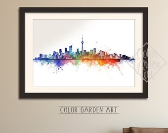 May include: A framed watercolor painting of the Toronto skyline with a rainbow color scheme. The painting is on a white background and is framed in black. The text "COLOR GARDEN ART" is printed below the painting.