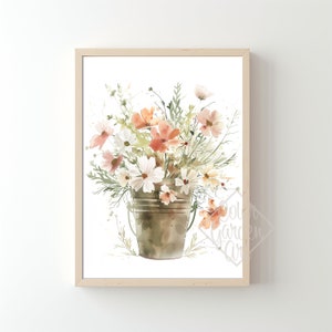 May include: A watercolor painting of a bouquet of peach and white flowers in a rustic metal bucket. The flowers are arranged in a loose, natural style, and the bucket is slightly weathered. The background is a simple white.