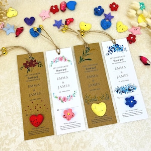 Könnte beinhalten: Vier Lesezeichen mit dem Text "Let Love Grow Thank You!" und den Namen "Emma & James" und dem Datum "20. April 2024". Jedes Lesezeichen hat ein anderes Blumendesign und ein kleines Saatguttütchen. Dekorative Herz-, Stern- und Blumenformen sind verstreut.