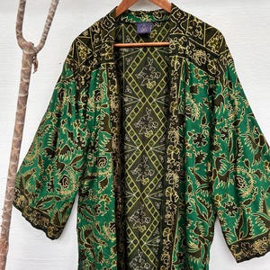May include: A green and gold silk kimono with a floral pattern. The kimono has a diamond pattern on the back.