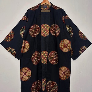 Può includere: Un kimono nero con un motivo geometrico di cerchi in tonalità di marrone, giallo e verde.