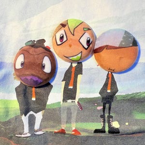 Puede incluir: Camiseta azul claro con tres personajes de dibujos animados con cabezas redondas y atuendos estilizados. Los personajes tienen cabezas naranjas, marrones y grises con atuendos negros y naranjas. Texto japonés en un rectángulo rojo en la parte inferior.