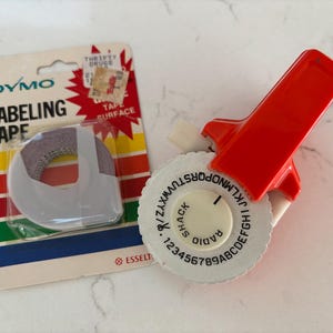 Vintage oranje Dymo-labelmaker en -tape voor radio-shack