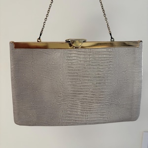 Cartera de mano tipo sobre de piel de serpiente color blanco roto de Etra, años 70, con asa pequeña de cadena dorada y herrajes y cierre dorados.
