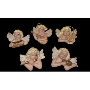 Könnte beinhalten: Fünf Engelsornamente mit blonden Haaren und glitzernden Flügeln. Jeder Engel spielt ein anderes Musikinstrument: ein Akkordeon, eine Laute, eine Harfe, eine Flöte und eine Geige. Die Ornamente sind beige und goldfarben.