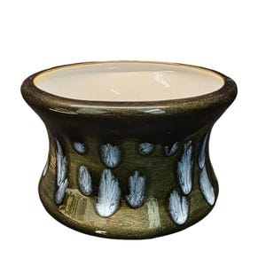 May include: A ceramic planter with a dark green exterior and a cream-colored interior. The planter has a unique design with white, dripped accents. The opening is approximately 4 inches in diameter.