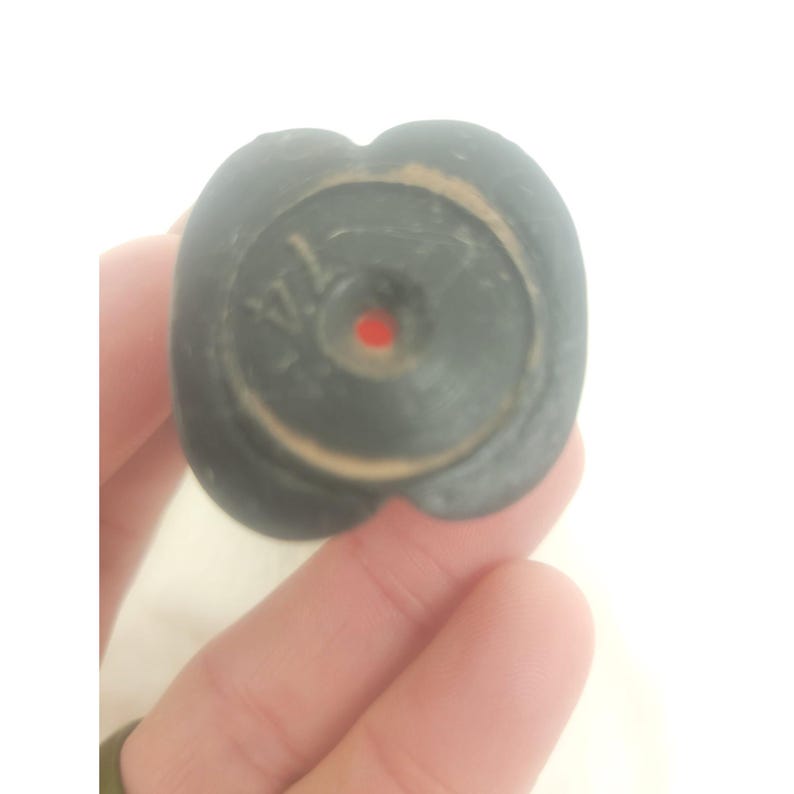 May include: Close-up of a black rubber stopper with a red dot in the center. The stopper has a raised circular design with the word "VLA" visible.