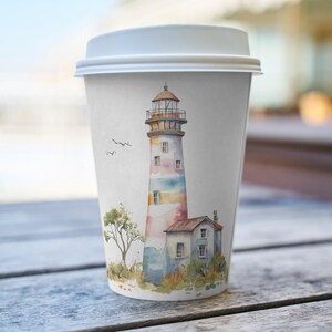 May include: A white paper coffee cup with a lid, featuring a watercolor illustration of a lighthouse. The lighthouse is painted with pastel colors and has a small building attached. Two birds fly in the sky near the lighthouse.