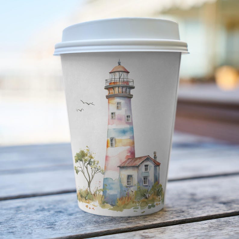 May include: A white paper coffee cup with a lid, featuring a watercolor illustration of a lighthouse. The lighthouse is painted with pastel colors and has a small building attached. Two birds fly in the sky near the lighthouse.