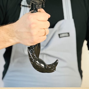 May include: A black umbrella with a bird-shaped handle. The handle is made of a smooth, black material and has a detailed design.