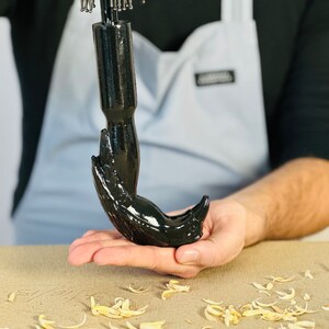 May include: A black, hand-shaped umbrella handle with a shiny finish. The handle is held in a person's hand.