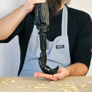 May include: A black umbrella with a unique, hand-shaped handle. The handle is made of a smooth, black material and resembles a human hand.
