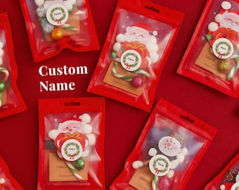 May include: Red plastic bags filled with Christmas-themed candies and decorations. The bags feature Santa Claus and snowman designs, along with candy canes and small gift tags. The text "Custom Name" is visible.