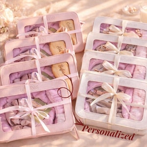 May include: Several pink and white gift boxes tied with ribbons. Each box contains a variety of items, including a personalized wooden brush. The word "Personalized" is printed on one of the boxes.
