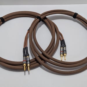 May include: Two brown speaker cables with gold-plated banana plugs on each end.