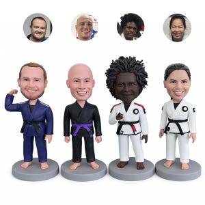 Puede incluir: Cuatro figuras de cabezas oscilantes de personas con uniformes de artes marciales. Las figuras están sobre bases grises y tienen caras sonrientes. Los uniformes son de varios colores, incluyendo azul, negro y blanco, con cinturones negros. Encima de las figuras hay cuatro retratos.