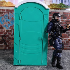 May include: A teal portable toilet with a white top stands next to a figure in a police uniform. The figure is holding a coffee cup. The background includes a brick wall and city buildings.