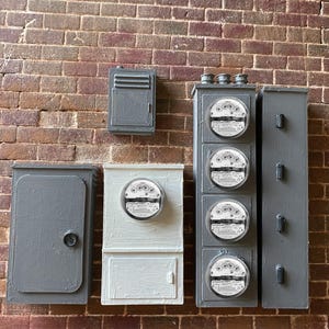 May include: A brick wall with five gray electrical boxes. Four of the boxes have round analog meters with black dials and white numbers. One box has a single door.