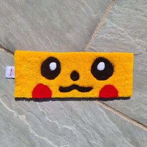 May include: A yellow doormat with a cartoon face. The face has black eyes with white pupils, a black moustache, and red cheeks.