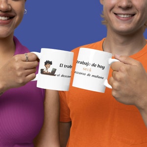 May include: Two white mugs with black text and a cartoon illustration. The mug on the left says "El trabajo de hoy sera el descanso de mañana". The mug on the right says "El trabajo de hoy sera el descanso de mañana".