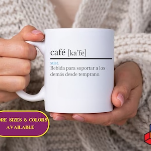 May include: White ceramic mug with a black and white definition of the word "cafe" in Spanish. The definition reads "sust. Bebida para soportar a los demás desde temprano." which translates to "sust. Drink to support others from early on."