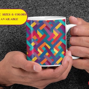 May include: White ceramic mug with a colorful geometric pattern of red, orange, yellow, green, blue, and purple. The mug has a handle on the right side.