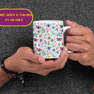 May include: White ceramic mug with a colorful pattern of bees, flowers, and leaves. The text "MORE SIZES & COLORS AVAILABLE" is printed on a purple banner.