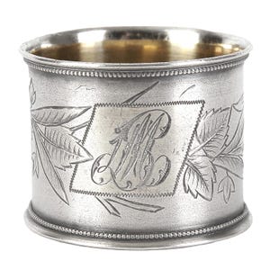 Peut inclure: Bague à serviette en argent avec un monogramme gravé et un motif de feuilles.